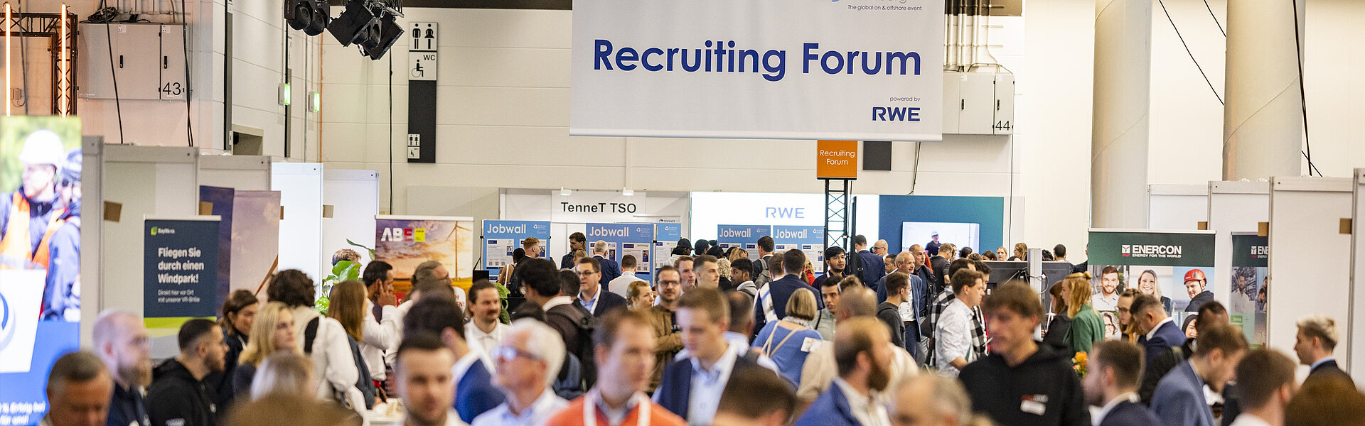 Blick über die Menschenmenge auf die Recruiting Area. Auf einem großen Schild, das von der Decke hängt, steht Recruiting Forum.