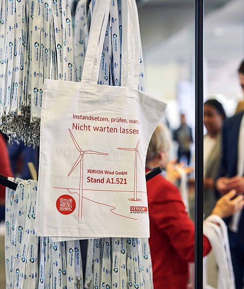 Ein Aufsteller mit Lanyards und Stofftaschen mit Sponsoren von der WindEnergy Hamburg